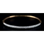 A DIAMOND SET STIFF HINGED BANGLE in 9ct gold set to the front with small eight cut stones,