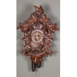 A BLACK FOREST CUCKOO CLOCK of conventional form, the cresting well carved with bird, vine leaves