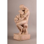 A PLASTER MODEL OF A NUDE MOTHER cradling two infants in her arms, she is seated on a stump,