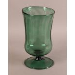 A GREEN GLASS PEDESTAL VASE, fluted cylindrical body of irregular form, waisted stem and circular