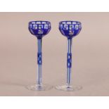 OTTO PRUTSCHER - A PAIR OF BLUE CASED WINE GLASSES, the panelled bowls with gilt wheel engraved