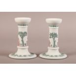 A PAIR OF WEDGWOOD THREE COLOUR DWARF CANDLESTICKS, relief decorated in green and mauve with
