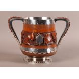 A VICTORIAN OAK TWO HANDLED CUP with silver plated mounts and interior, the tapered body finely