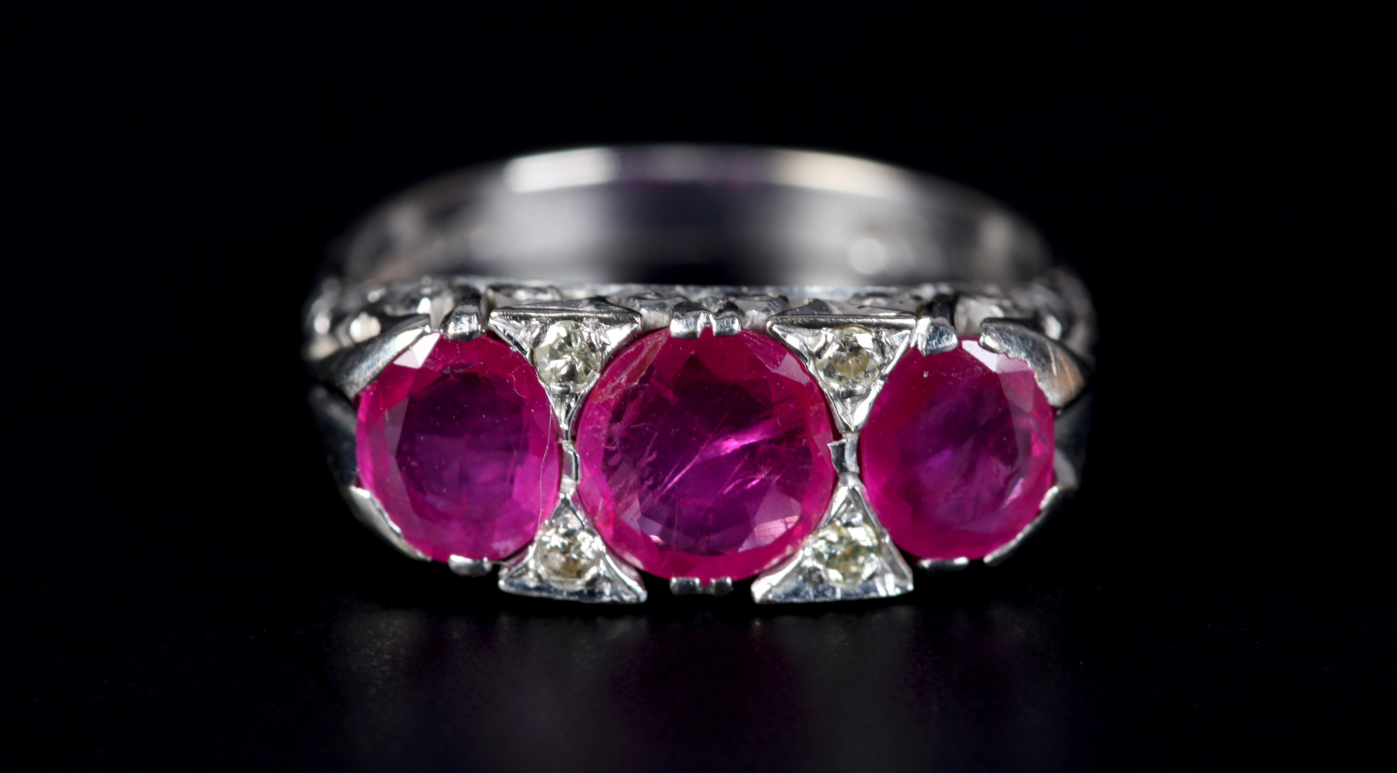 A RUBY AND DIAMOND RING in 18ct white gold the three graduated oval faceted rubies claw set inline