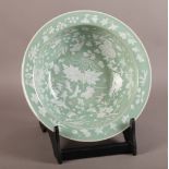 A CHINESE CELADON GLAZED CIRCULAR BOWL decorated overall in shallow relief white glaze with