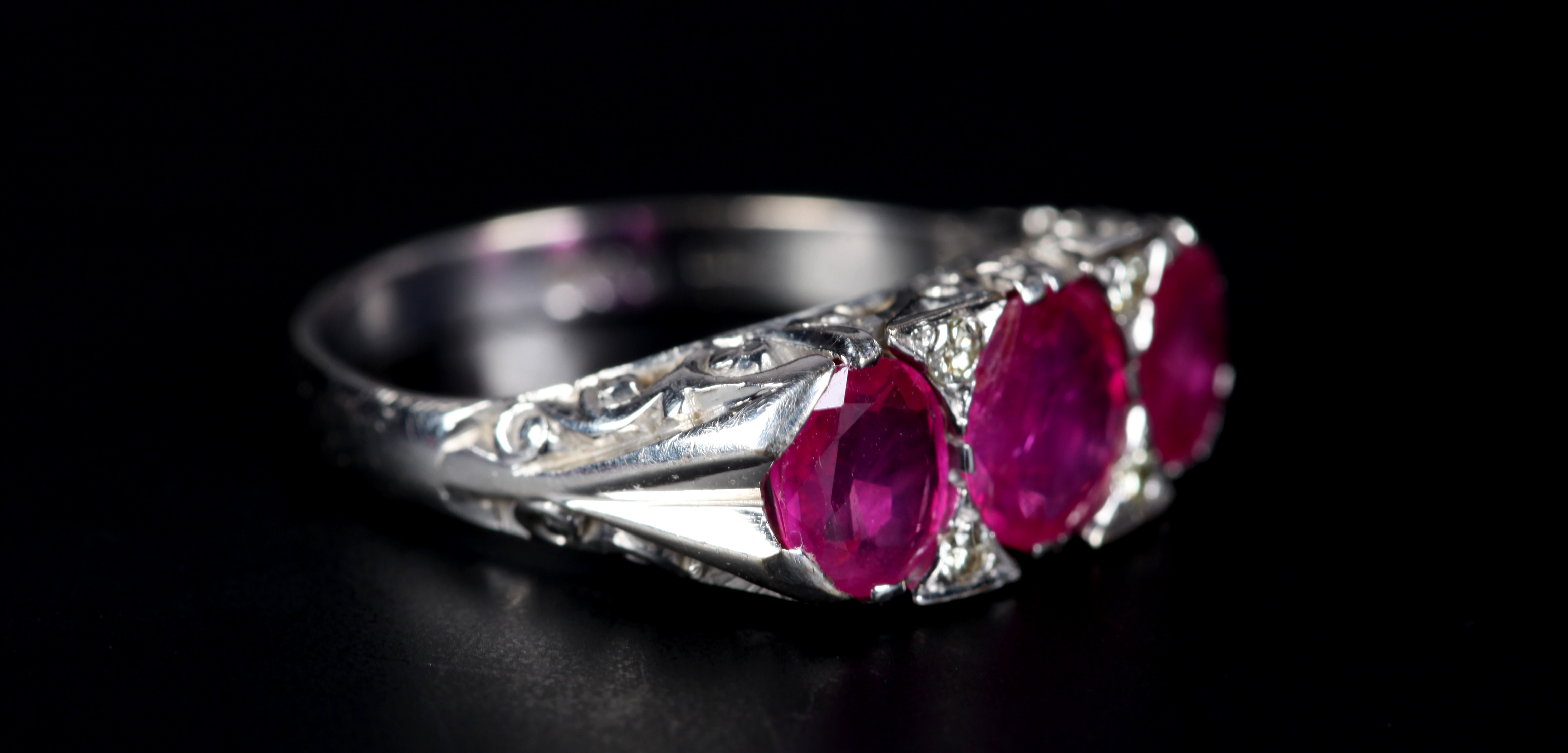 A RUBY AND DIAMOND RING in 18ct white gold the three graduated oval faceted rubies claw set inline - Image 2 of 2