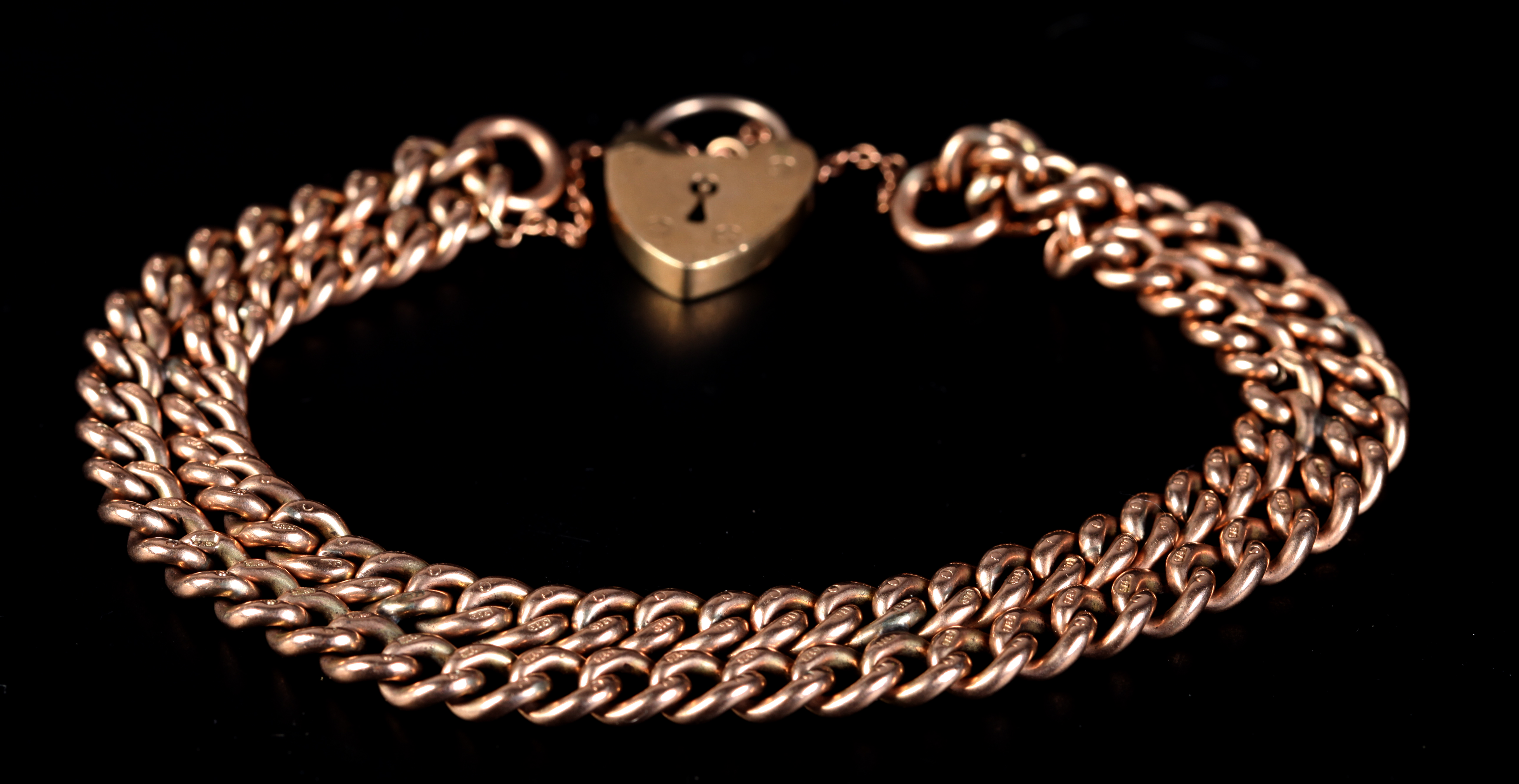 A BRACELET in 9ct rose gold of double curb links closed with a padlock fastener, total approximate