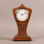 AN ART NOUVEAU MAHOGANY MANTEL CLOCK of angular arched and waisted outline inlaid with pewter, brass