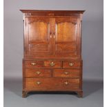 A GEORGE III OAK CLOTHES PRESS, having a moulded cornice above two ogee arch field panel doors,