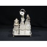 A Six Bottle Cruet Set With Silver Mounts On A Plated Stand