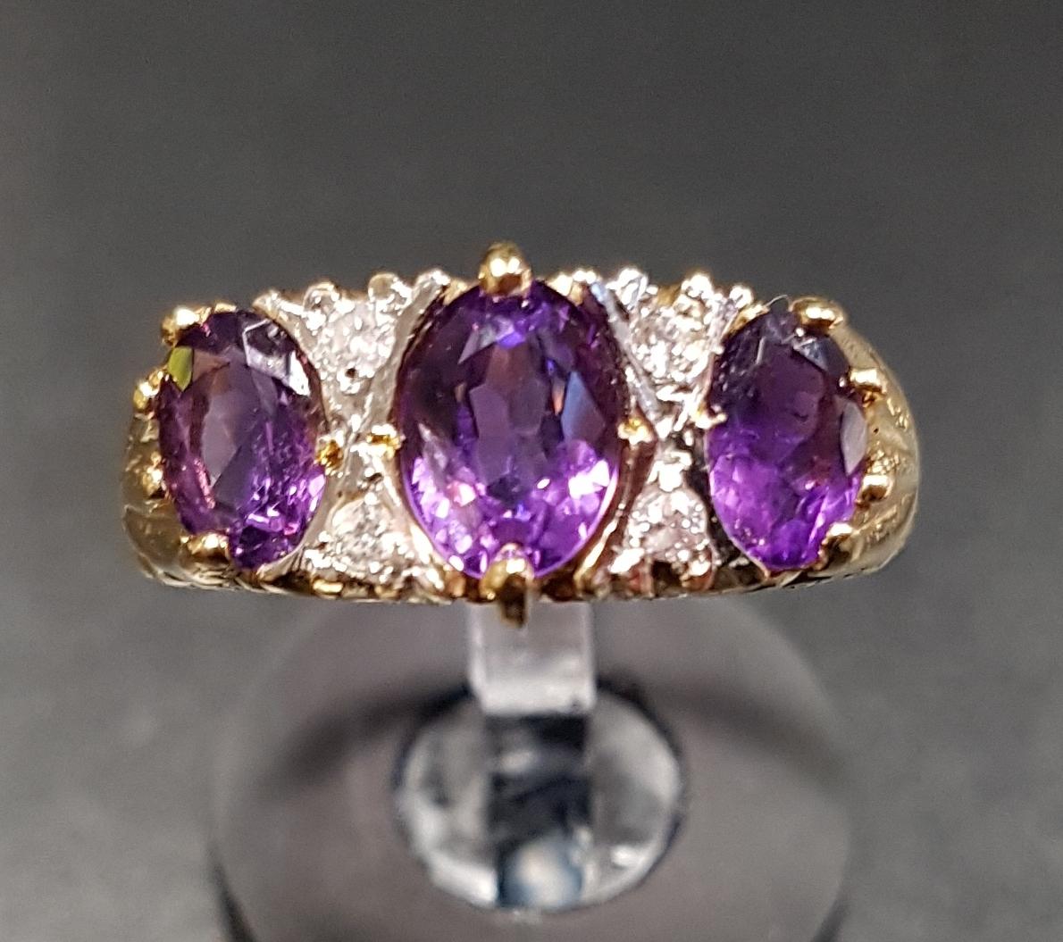 AMETHYST AND DIAMOND RING the three graduated oval cut amethysts separated by small diamonds, on