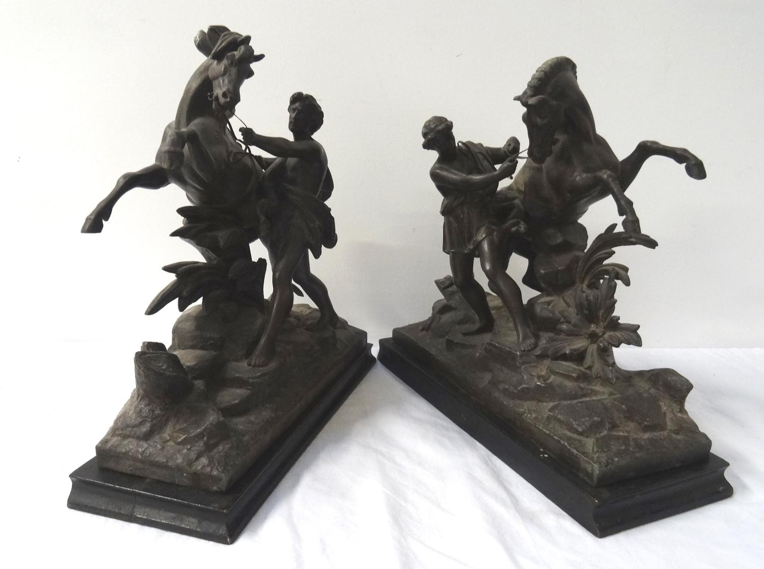 TWO SPELTER FIGURINES each depicting a man trying to control a rearing horse, raised on ebonised