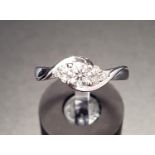 PRETTY TWIST SET DIAMOND RING the central round brilliant cut diamond flanked by three small