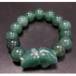 GREEN AGATE BEAD BRACELET comprising thirteen beads and a carved dog of foe style section