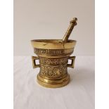 BRASS MORTAR AND PESTLE of tapering form with embossed decoration