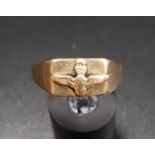 NINE CARAT GOLD RING with raised decoration of wings surmounted by a crown, ring size V and
