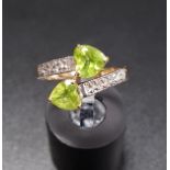 PERIDOT AND DIAMOND CROSSOVER RING the two heart shaped peridots flanked by diamond set shoulders,