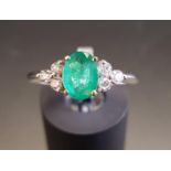 EMERALD AND DIAMOND RING the central oval cut emerald approximately 0.74cts flanked by three