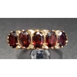 GARNET FIVE STONE RING the five oval cut garnets on nine carat gold shank with scroll decorated