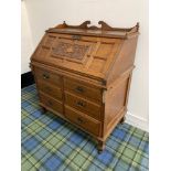 CARVED OAK BUREAU with a shaped galleried top above a panelled fall flap with an inset leather