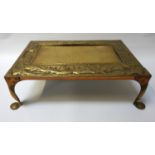 ARTS AND CRAFTS BRASS TRIVET of rectangular form with embossed flower decoration, standing on scroll