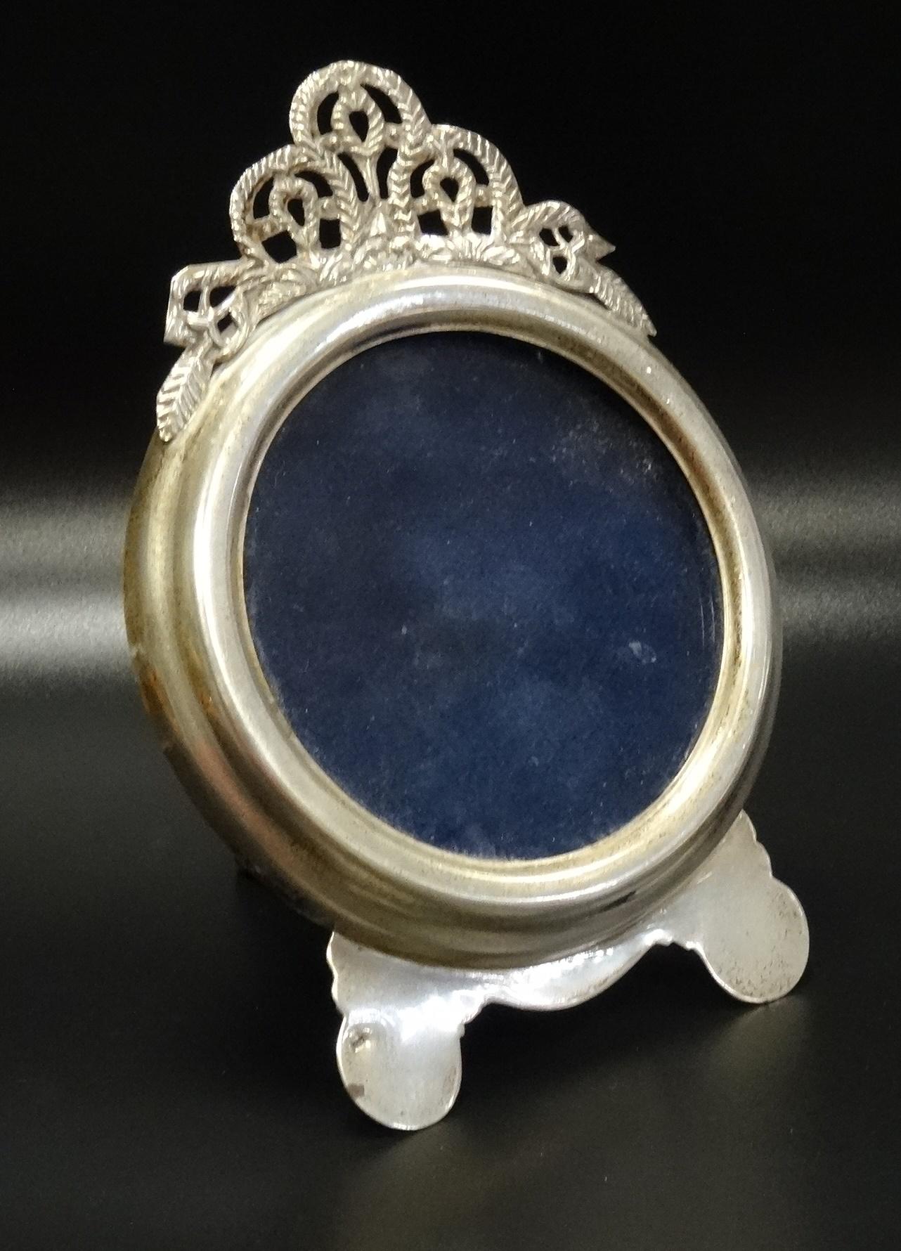 SILVER PHOTOGRAPH FRAME the circular frame below a decorative pierced top section, on easel support,