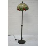 TIFFANY STYLE STANDARD LAMP with a dome shaped leaded shade decorated with a green and red leaf rim,