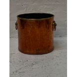 COPPER LOG BIN of cylindrical form with a brass band collar, and lion mask handles, 31cm high