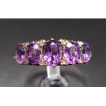 GRADUATED OVAL CUT AMETHYST FIVE STONE RING with small diamond accents, on eighteen carat gold