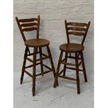 PAIR OF OAK BAR STOOLS with ladder backs, circular seats and raised on turned legs with stretchers