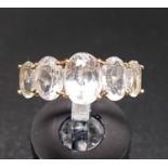 GRADUATED CLEAR QUARTZ FIVE STONE RING on ten carat gold shank with decorative split shoulders, ring