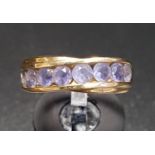 IOLITE HALF ETERNITY RING the channel set gemstones in fourteen carat gold with twist setting,