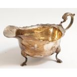 GEORGE VI SILVER SAUCE BOAT with shaped rim, scroll handle and raised on three shaped pad feet,