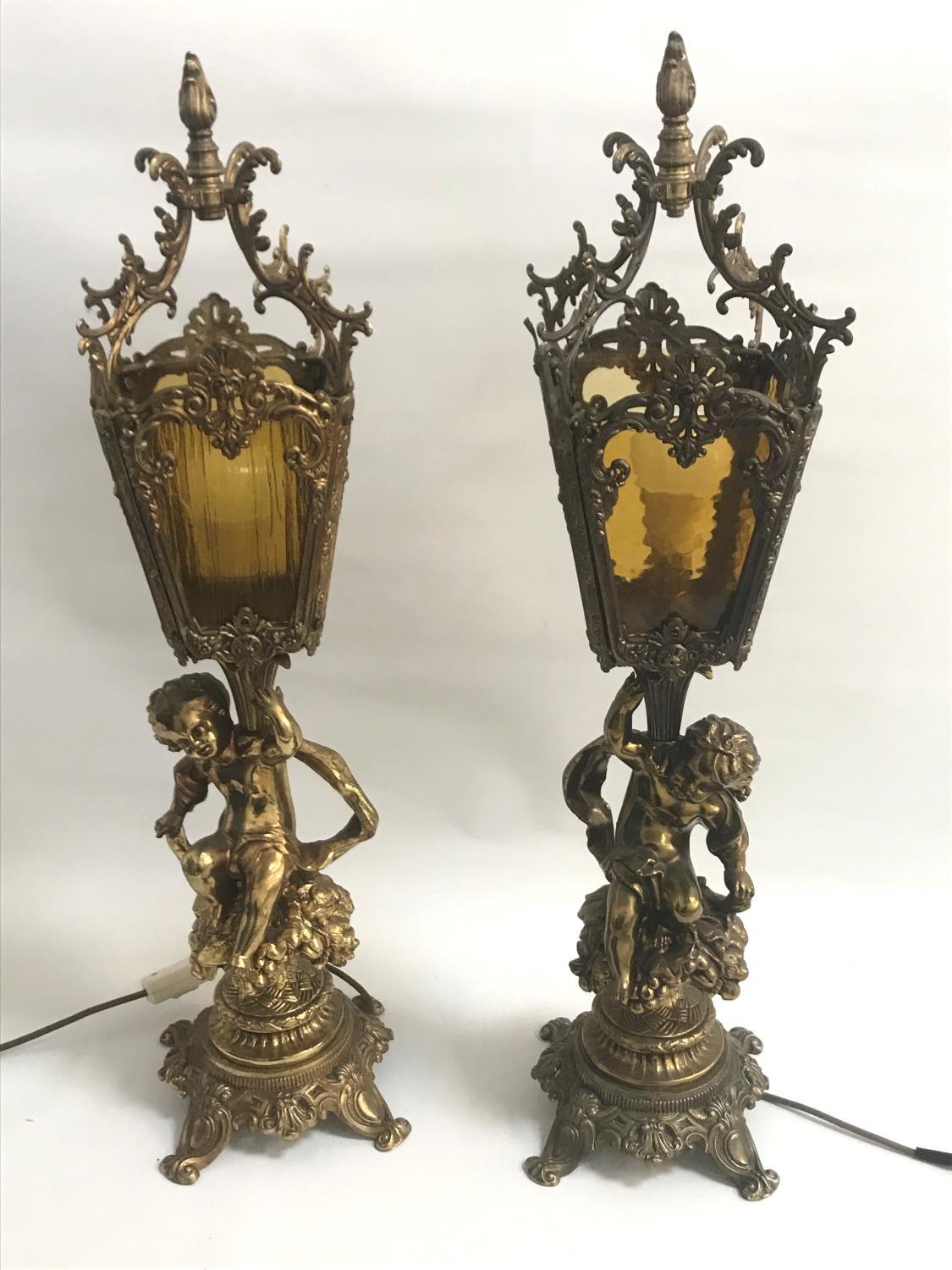 LARGE PAIR OF GILT METAL LAMPS the columns with putti seated on bushes below four sided mottled