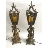 LARGE PAIR OF GILT METAL LAMPS the columns with putti seated on bushes below four sided mottled