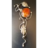 AMBER SET PENDANT the oval cabochon amber section in unmarked silver scroll and foliate mount,