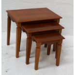 TEAK NEST OF TABLES with cross banded tops above a shaped frieze, standing on shaped supports,