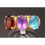 AMETHYST, GARNET AND BLUE TOPAZ THREE STONE RING the three oval cut gemstones on ten carat gold