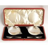 CASED PAIR OF GEORGE V SILVER PICKLE DISHES AND FORKS each of the circular dishes with two