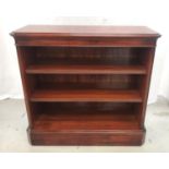 MAHOGANY AND CROSSBANDED BOOKCASE with a moulded top with canted corners flanking adjustable