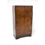 WALNUT WARDROBE of small proportions, with a moulded top above two doors opening to reveal a hanging