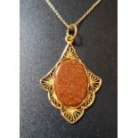 GOLDSTONE SET PENDANT the central oval goldstone section in attractive shaped and pierced unmarked