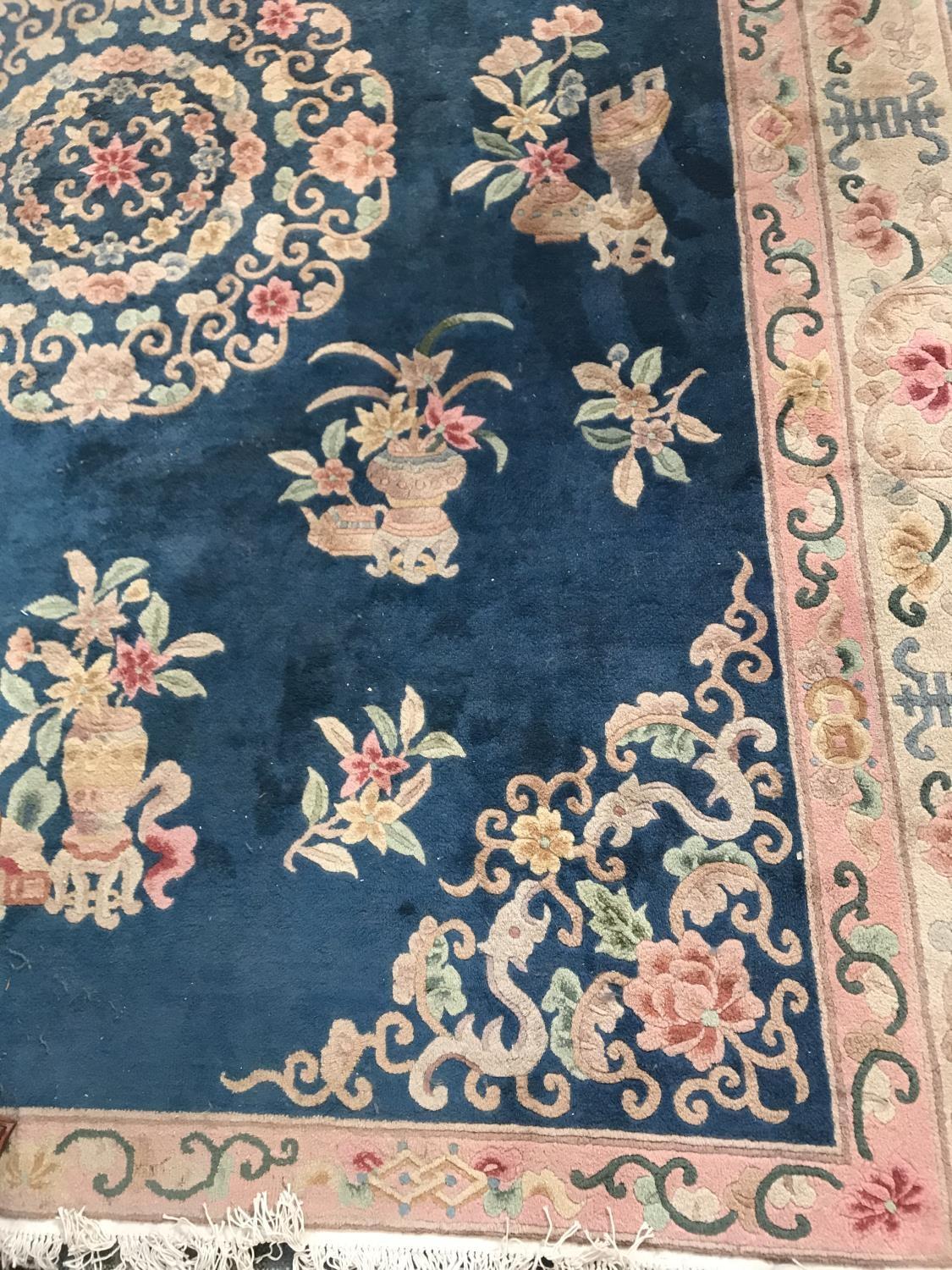 LARGE CHINESE STYLE RUG with a Royal blue ground decorated with floral motifs, encased in a floral