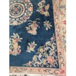 LARGE CHINESE STYLE RUG with a Royal blue ground decorated with floral motifs, encased in a floral