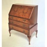 WALNUT BUREAU with a crossbanded fall flap opening to reveal a fitted interior above three graduated