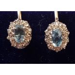 PAIR OF AQUAMARINE AND DIAMOND CLUSTER EARRINGS the central oval cut aquamarines in diamond