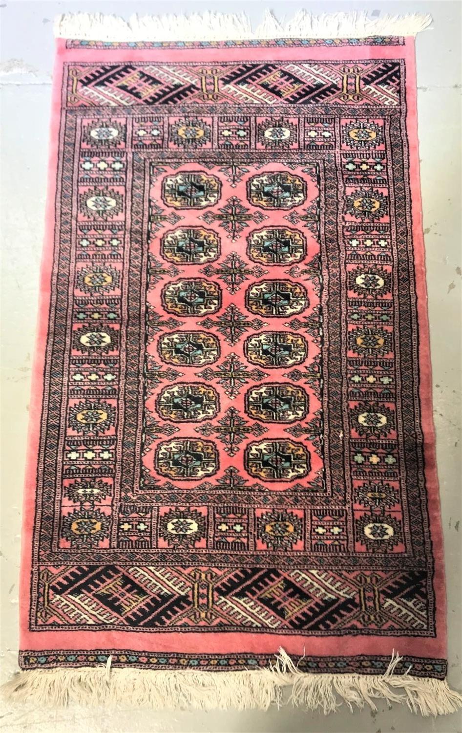 MIDDLE EASTERN PRAYER RUG with a pink ground and multi lozenge central section encased by a