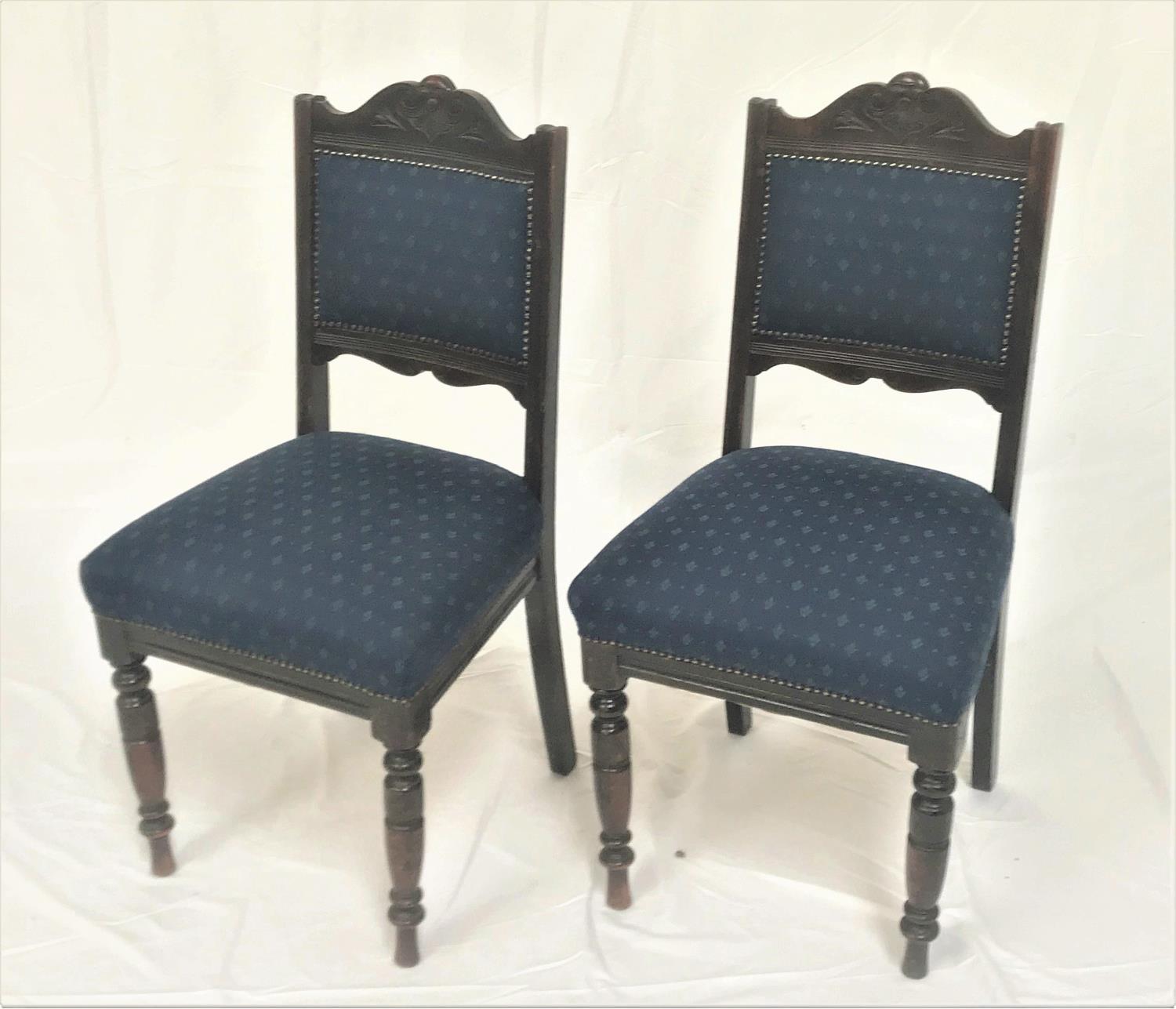 PAIR OF EDWARDIAN OAK DINING CHAIRS with shaped top rails above padded backs and stuffover seats