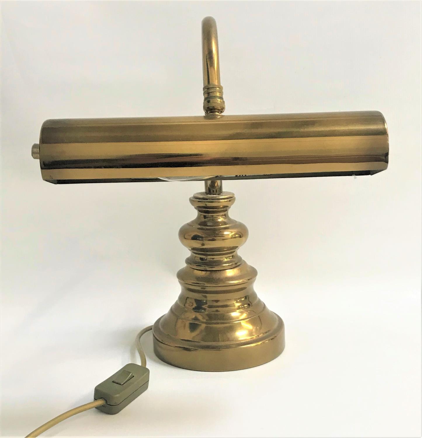 BRASS DESK LAMP raised on a circular stepped base with a shaped arm and tubular adjustable shade,