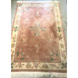 LARGE CHINESE WASH RUG with a mushroom coloured ground decorated with floral motifs and encased by a